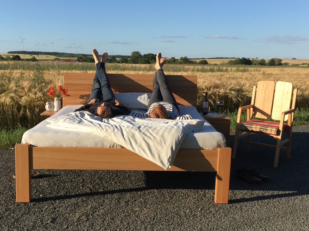 Zwei Personen liegen kopfüber auf einem Bett an einem Feld in der Natur